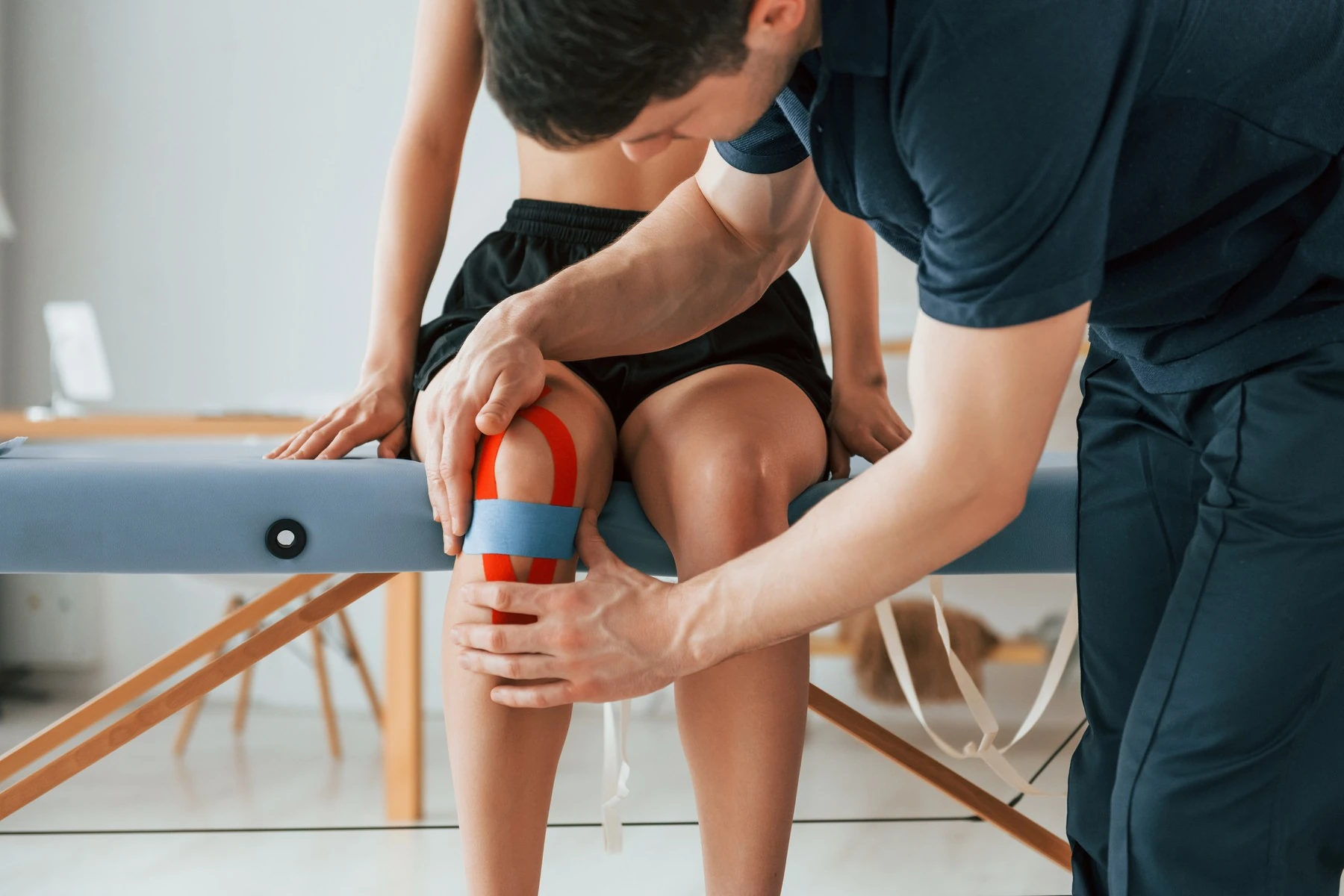 Colocación de un vendaje funcional sobre la rodilla del paciente, en un tratamiento de Fisioterapia traumatológica y deportiva de Clínica Malai en Bilbao y Mungia
