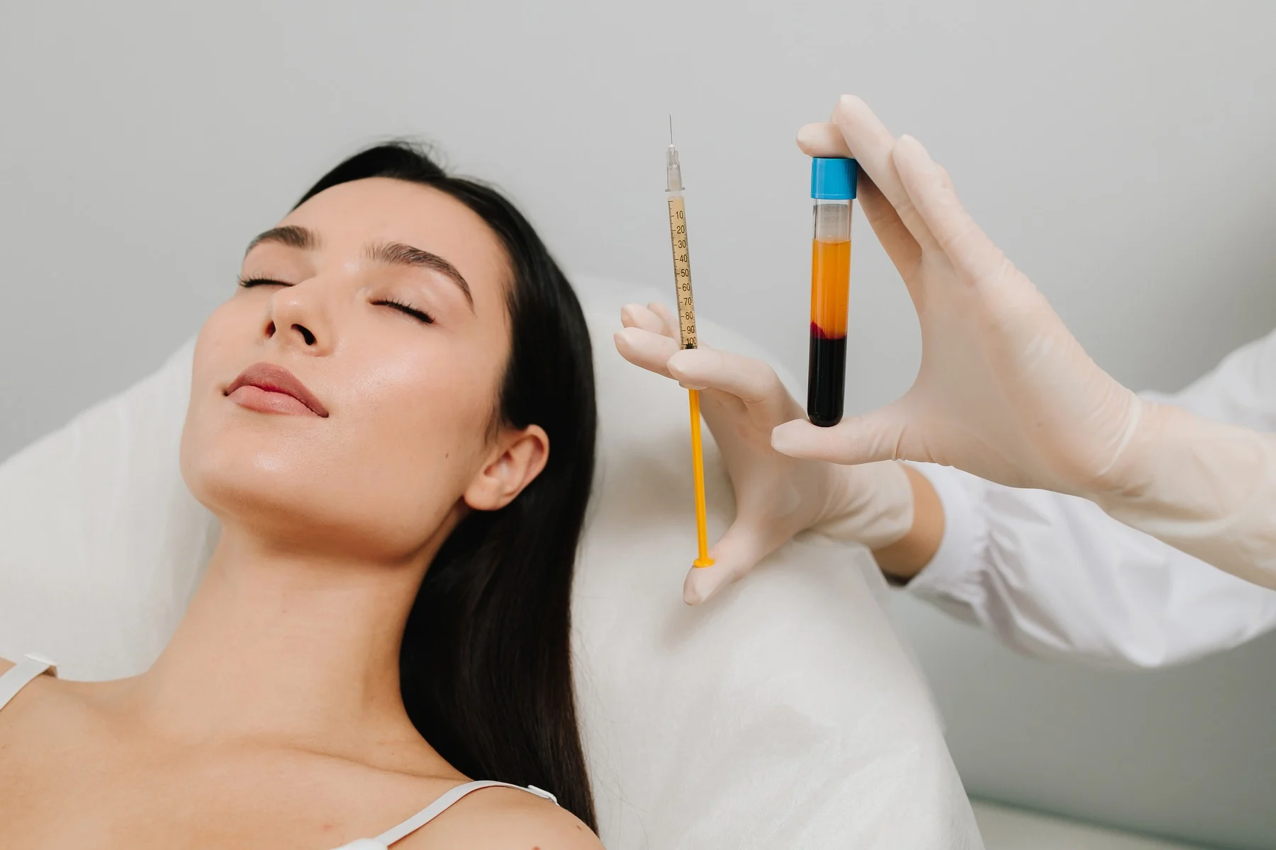 Plasma rico en plaquetas (PRP) en Bilbao: la profesional sanitaria sostiene el tubo con el plasma separado junto a la paciente antes de la sesión facial