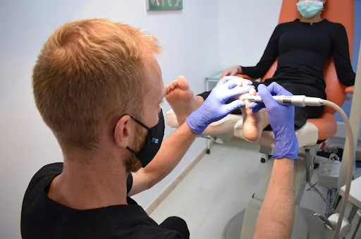 Podólogo de Clínica Malai tratando el pie de una paciente con el torno podológico, en Mungia